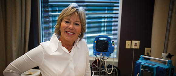 a blond woman in a white shirt smiles at the camera