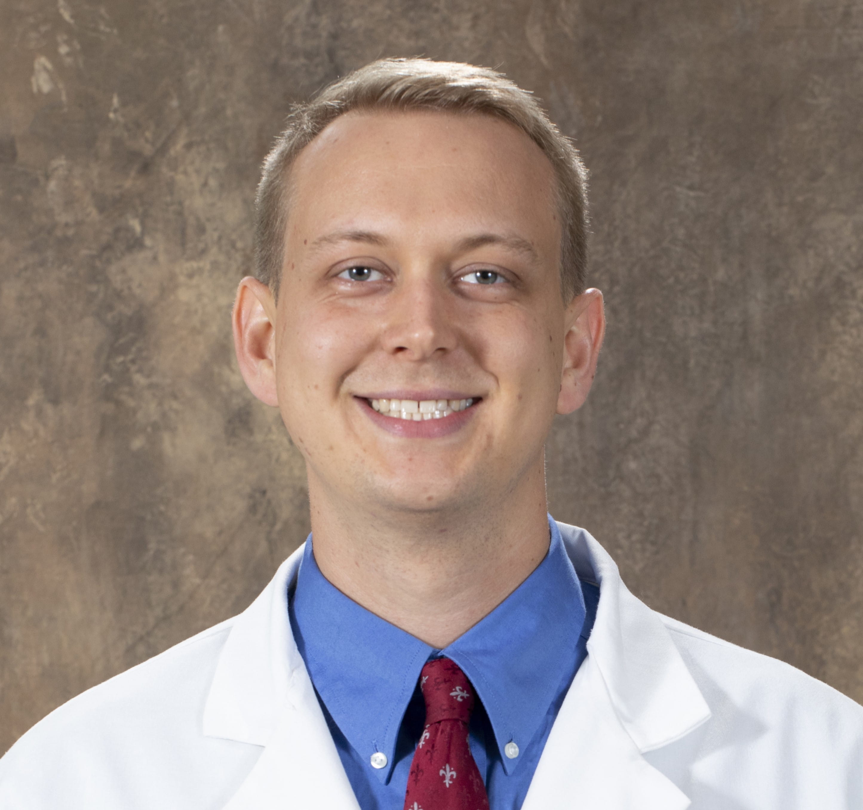 David Gunderman, a white man in a blue shirt, red tie, and white lab coat