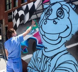 Payton Miller paints a mural at the First Annual Artists on the Plaza event