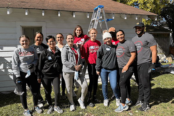 IU School of Medicine student standing together in front of building they are repairing.