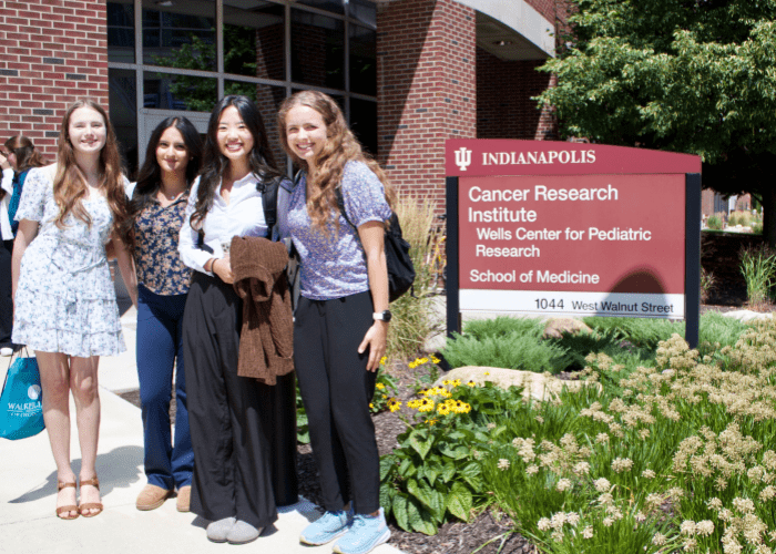 Four female student interns pose next to the Wells Center's sign