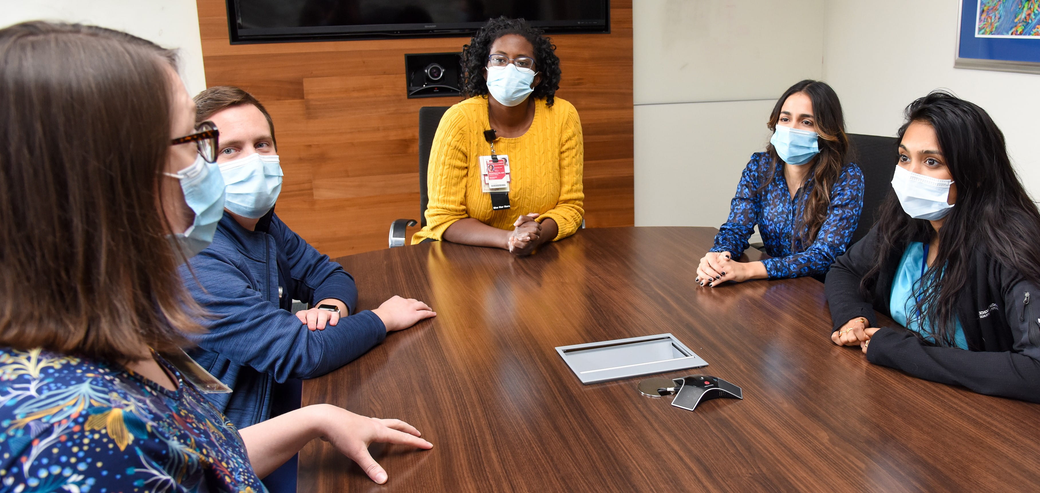 Three faculty members standing next to one another reviewing brain scans on screens.