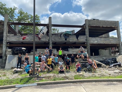 a group of students outside in front of a crumbling structure