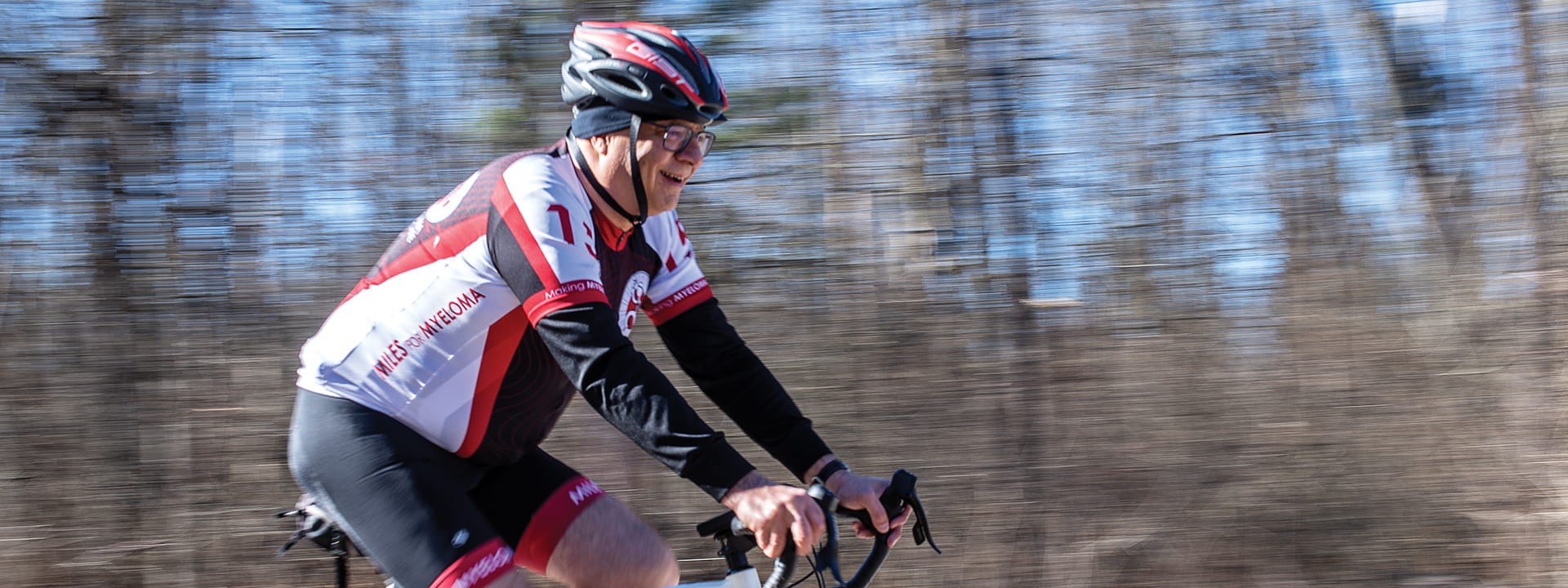 rafat abanour rides a bicycle with blurred trees in the background