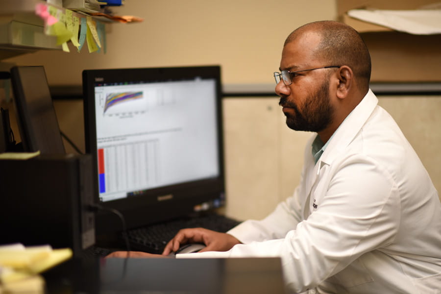 a student working at a computer station wearing a white lab coat