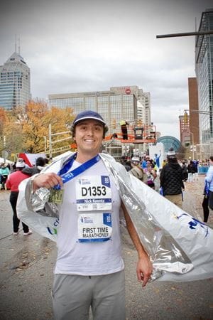 a person in running gear holds up their medal after completing the race
