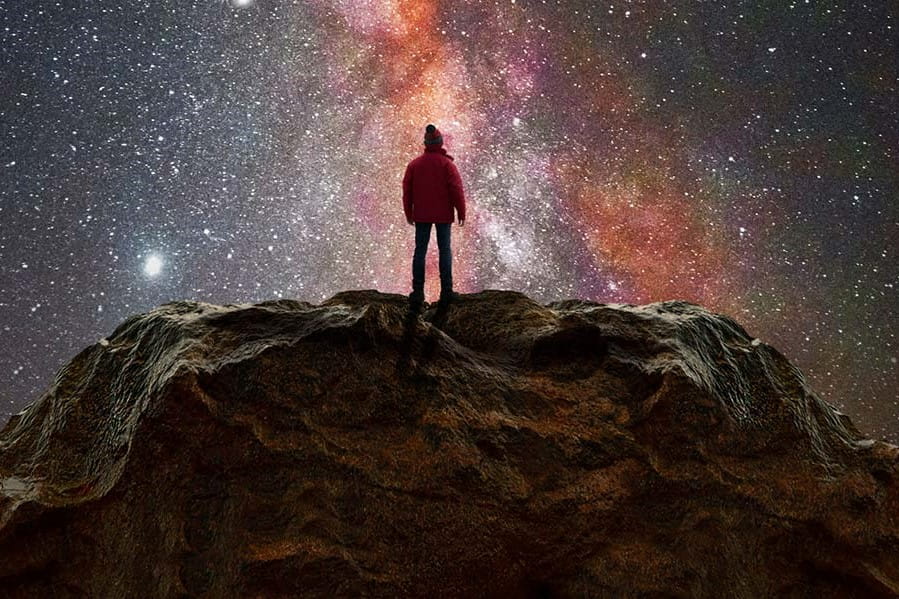 a silhouette of a person is visible in front of a night sky showing the milky way