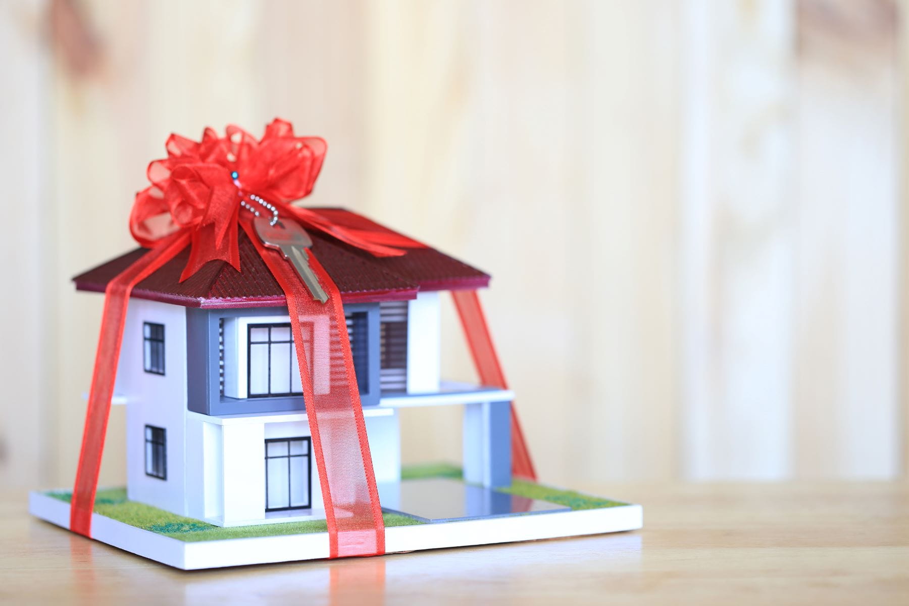 a model of a house with a red bow tied around it and the key dangling from the bow