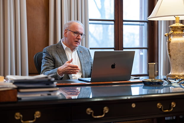 Jay Hess with a laptop sitting at a desk