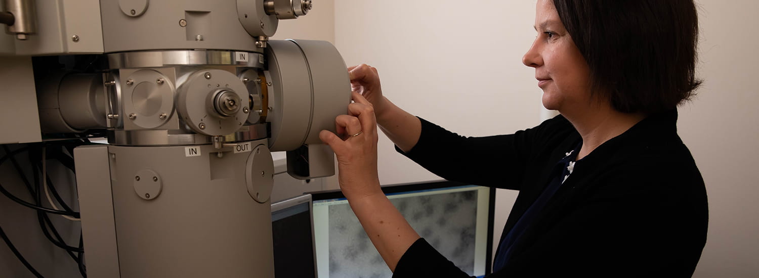 A researcher carefully adjusts the settings on a sophisticated electron microscope, focusing on the intricate details required for high-resolution imaging. 