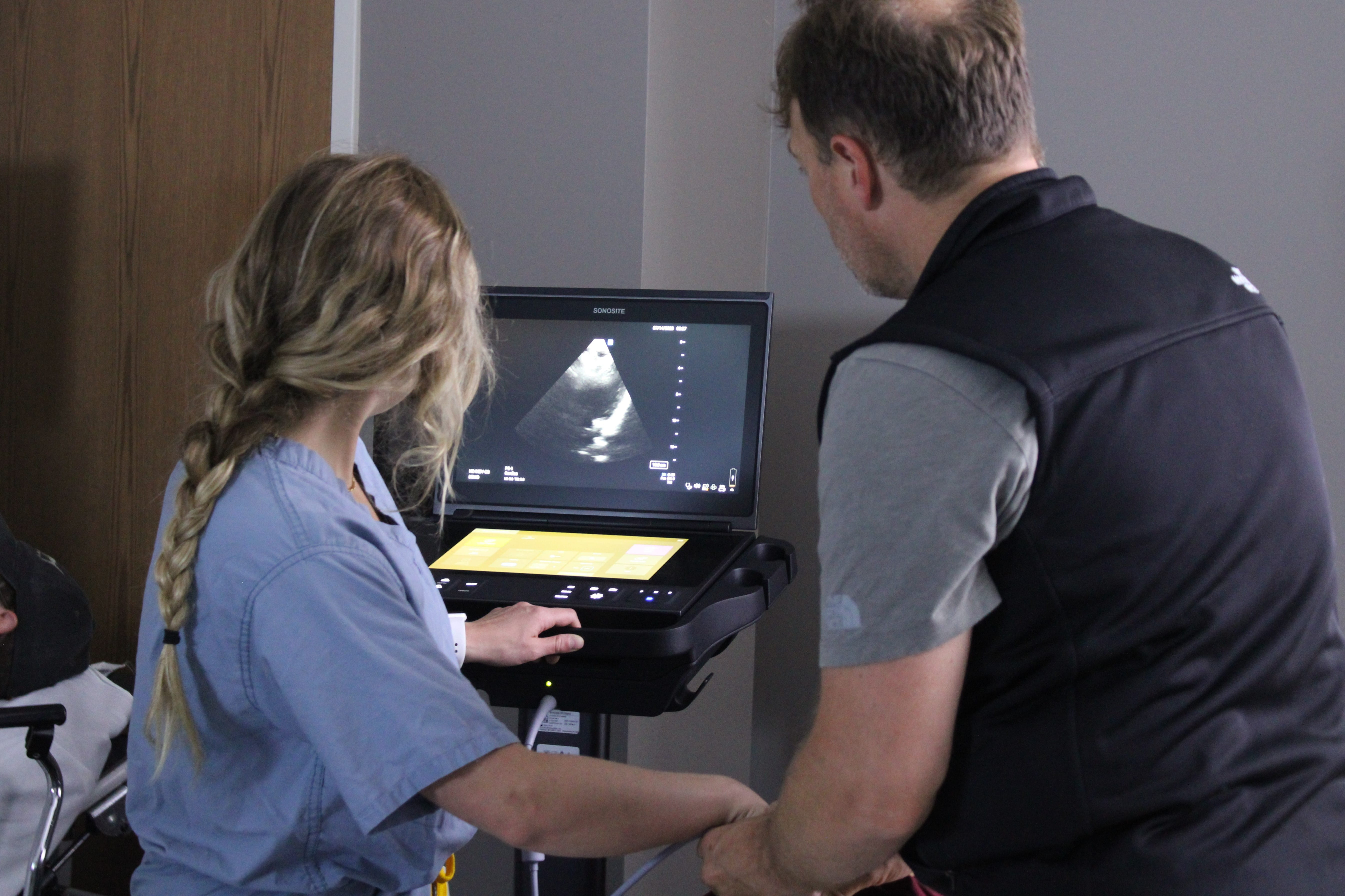 an ultrasound screen is visible over the shoulder of two providers