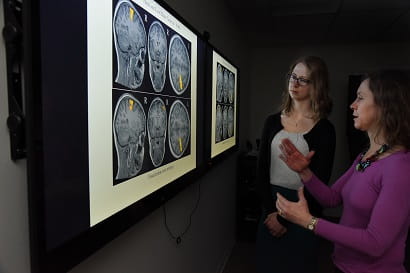 Faculty members looking at brain scans on an illuminated wall