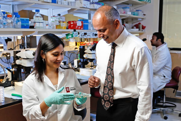 chandy john speaks with students in his lab